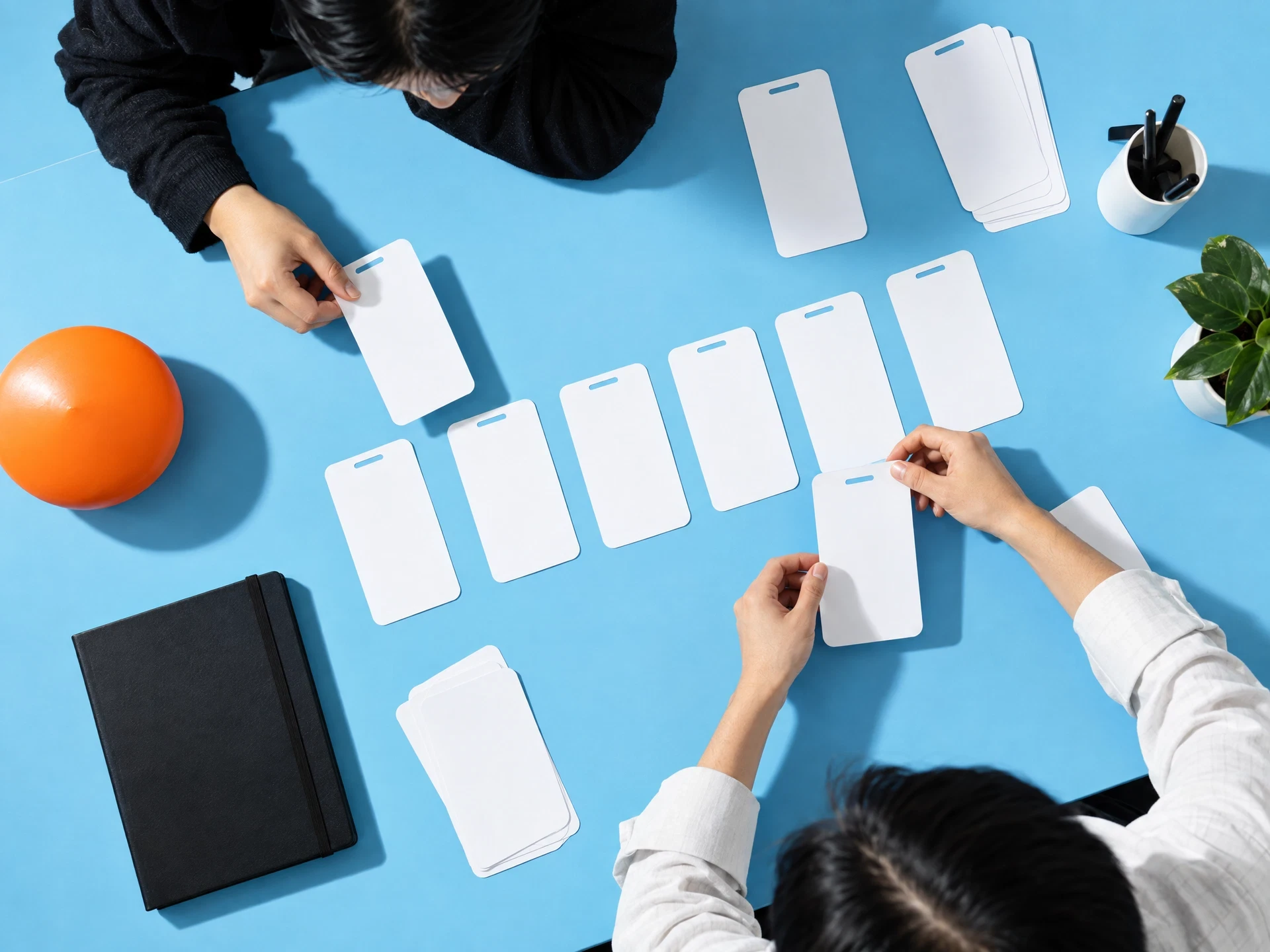 Collaborators arranging blank phone frames on a blue table